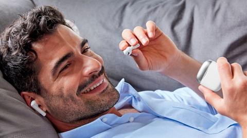 Man ligt ontspannen neer met Silvercrest True Wireless oortjes in zijn oren en houdt oplaaddoosje vast